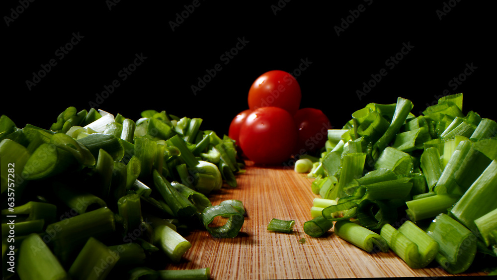 Cutting, cooking process, tasty and bright image, green onion with a bright tomato, on a dark background. Cutting, cooking process, tasty and bright image, green onion with a bright tomato, on a dark background.