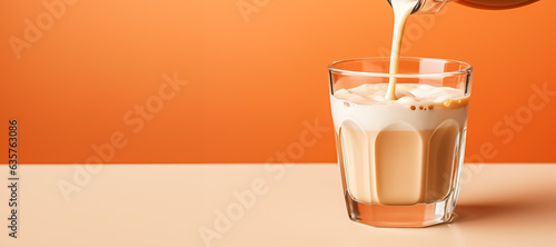 Foto Pouring milk into glass of coffee latte isolated on pastel background with a cop