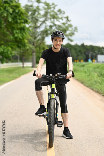 Full length male cyclist in sport clothing and helmet riding bicycle on the road. Sport, active life and healthy lifestyle concept. © Prathankarnpap