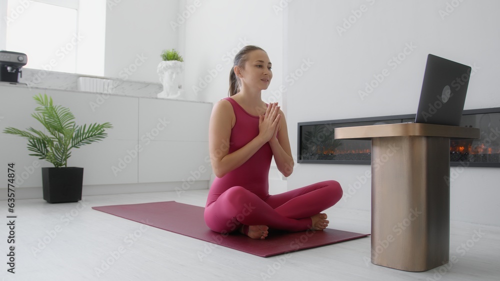 Yoga instructor teaching online class in modern living room. Pilates and stretching coach streaming workout from home Yoga instructor teaching online class in modern living room. Pilates and stretching coach streaming workout from home
