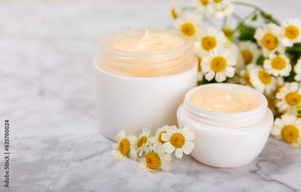 Open jar of moisturizing cream for face, body and hands with a chamomile flower on a light background. Herbal dermatological cosmetic hygiene cream. Natural cosmetic product. Beauty concept. MOCKUP Open jar of moisturizing cream for face, body and hands with a chamomile flower on a light background. Herbal dermatological cosmetic hygiene cream. Natural cosmetic product. Beauty concept. MOCKUP