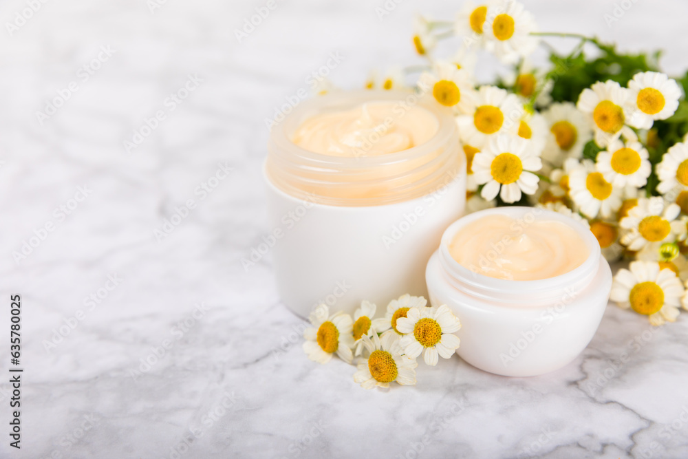 Open jar of moisturizing cream for face, body and hands with a chamomile flower on a light background. Herbal dermatological cosmetic hygiene cream. Natural cosmetic product. Beauty concept. MOCKUP Open jar of moisturizing cream for face, body and hands with a chamomile flower on a light background. Herbal dermatological cosmetic hygiene cream. Natural cosmetic product. Beauty concept. MOCKUP