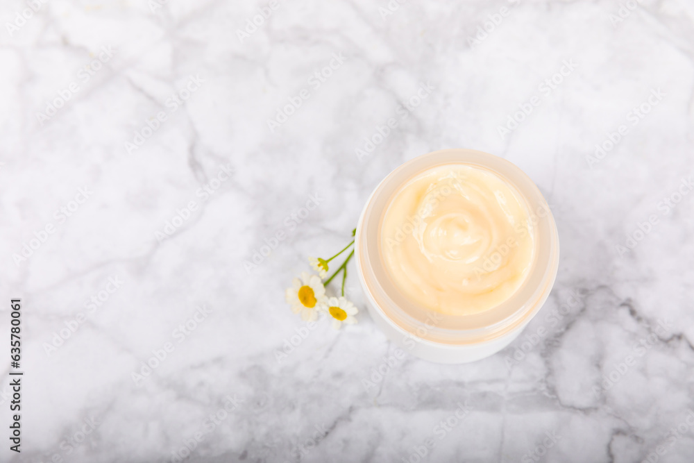 Open jar of moisturizing cream for face, body and hands with a chamomile flower on a light background. Herbal dermatological cosmetic hygiene cream. Natural cosmetic product. Beauty concept. MOCKUP Open jar of moisturizing cream for face, body and hands with a chamomile flower on a light background. Herbal dermatological cosmetic hygiene cream. Natural cosmetic product. Beauty concept. MOCKUP
