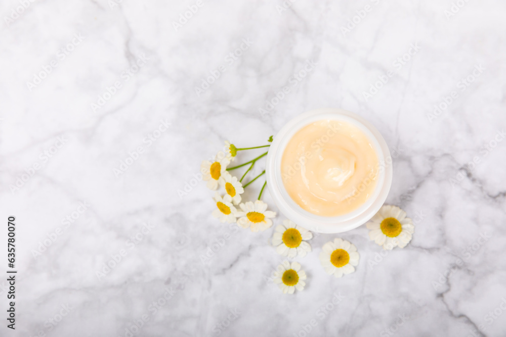 Open jar of moisturizing cream for face, body and hands with a chamomile flower on a light background. Herbal dermatological cosmetic hygiene cream. Natural cosmetic product. Beauty concept. MOCKUP Open jar of moisturizing cream for face, body and hands with a chamomile flower on a light background. Herbal dermatological cosmetic hygiene cream. Natural cosmetic product. Beauty concept. MOCKUP