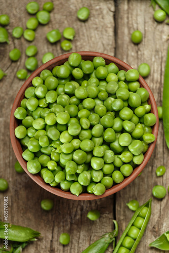 Green peas in closed and open pods, peeled peas in a bowl, scattered pea seeds on a wooden background, top view © Denis