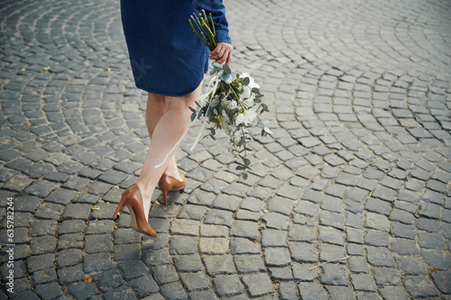 Legs, walking forward. Close up view of woman that is with flowers in hands