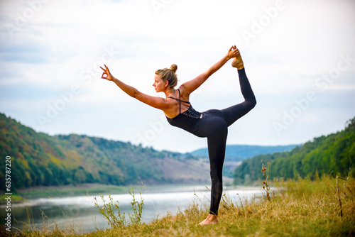 the girl does yoga on the river bank