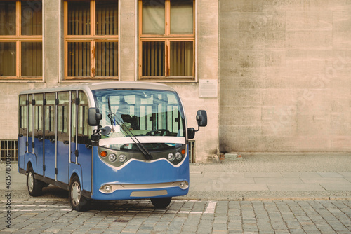 A small electric tour bus is waiting for passengers near the administrative building. photo