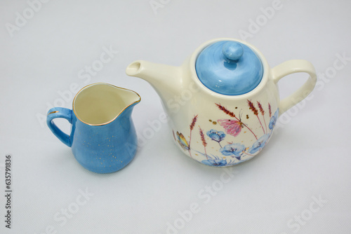 Mock up - design set of elegant and traditional teapot colorful white and blue coffee cup and Tea cup on cup's plate beside the hot tea pot , flowers and butterflies drawn on the ceramic mug cup