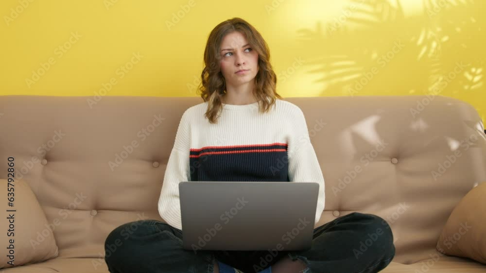 Front view of thoughtful girl learning on laptop at home. Smart student doing homework. Serious woman focused on e-learning. Concentrated lady sitting on couch with computer in room, 4k footage Front view of thoughtful girl learning on laptop at home. Smart student doing homework. Serious woman focused on e-learning. Concentrated lady sitting on couch with computer in room, 4k footage