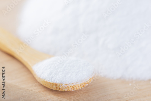 White sugar with a spoon on a wooden board, sweet food, selective focus.