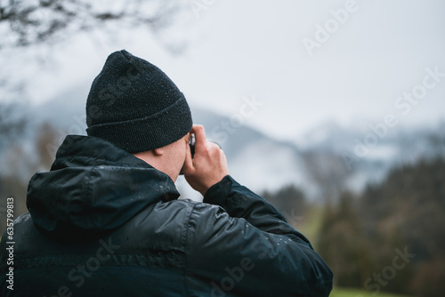 Capturing Alpine Beauty. Man Photographer Capturing professional images of Snow-Capped Peaks in Wanderlust Moment. Concept of vacation in Europe.