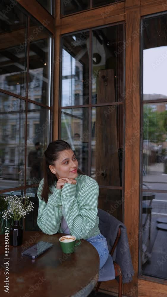 With a coffee cup in hand and her smartphone nearby, the dynamic and youthful girl relishes the summer vibes at the café's outdoor seating. With a coffee cup in hand and her smartphone nearby, the dynamic and youthful girl relishes the summer vibes at the café's outdoor seating.
