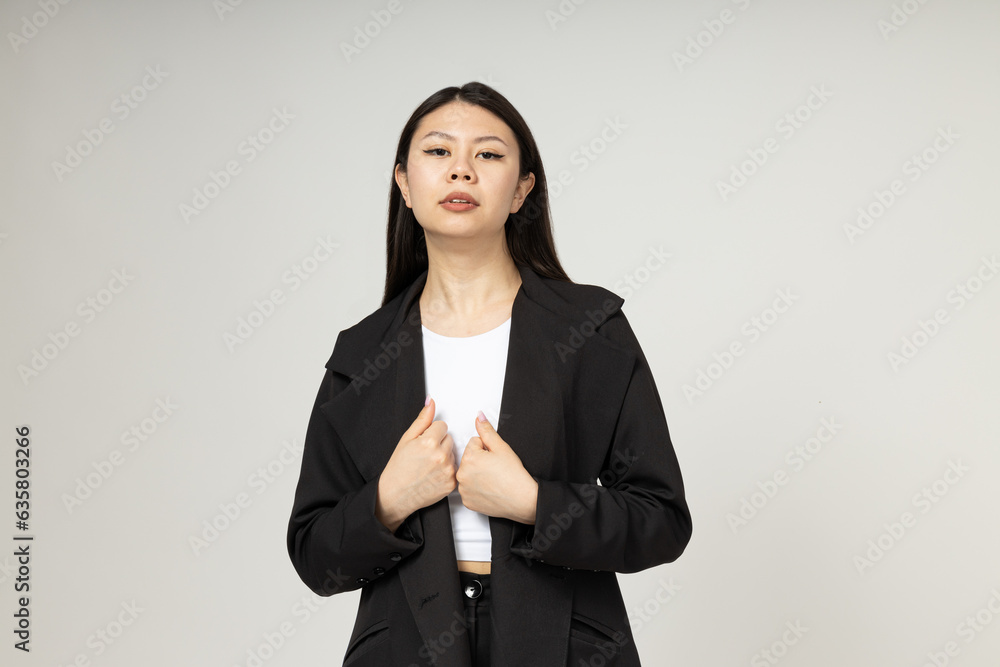 Serious Asian girl dressed in classic austere style on gray background Serious Asian girl dressed in classic austere style on gray background