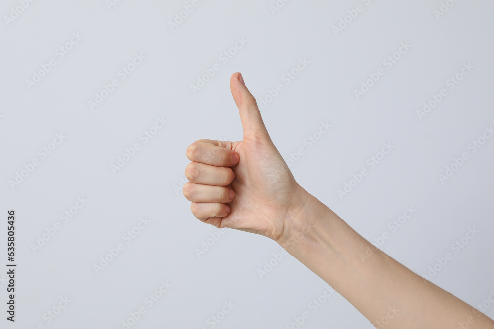 Female hand showing thumb up on light background