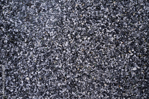 Small pebble stone background, dark wet gravel and gray dry gravel. Black small road