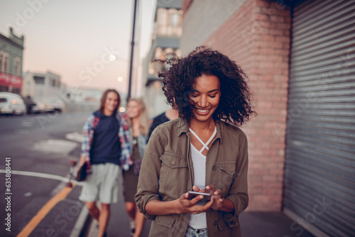 Young woman using a smart phone with her diverse and mixed group of friends behind her photo