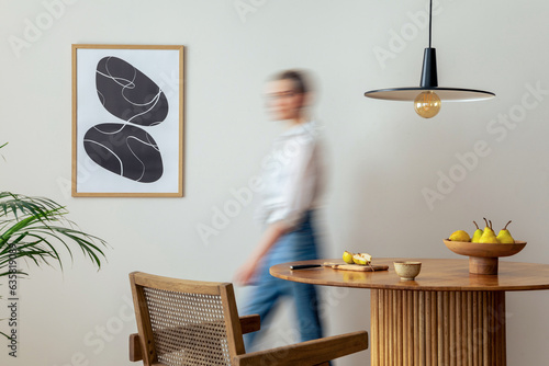 Cuadro en lienzo Interior design of domestic dining room space with two mock up poster frames, round table, chair, pedant lamp, decoration and woman in jeans