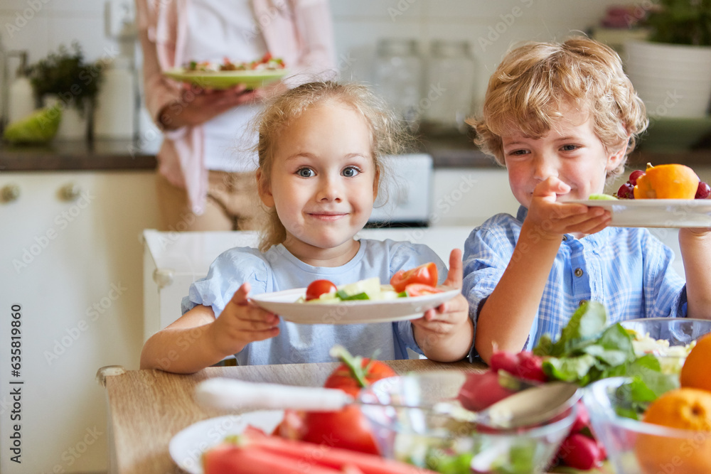Smiling girl sitting with brother holding fruit plate Smiling girl sitting with brother holding fruit plate