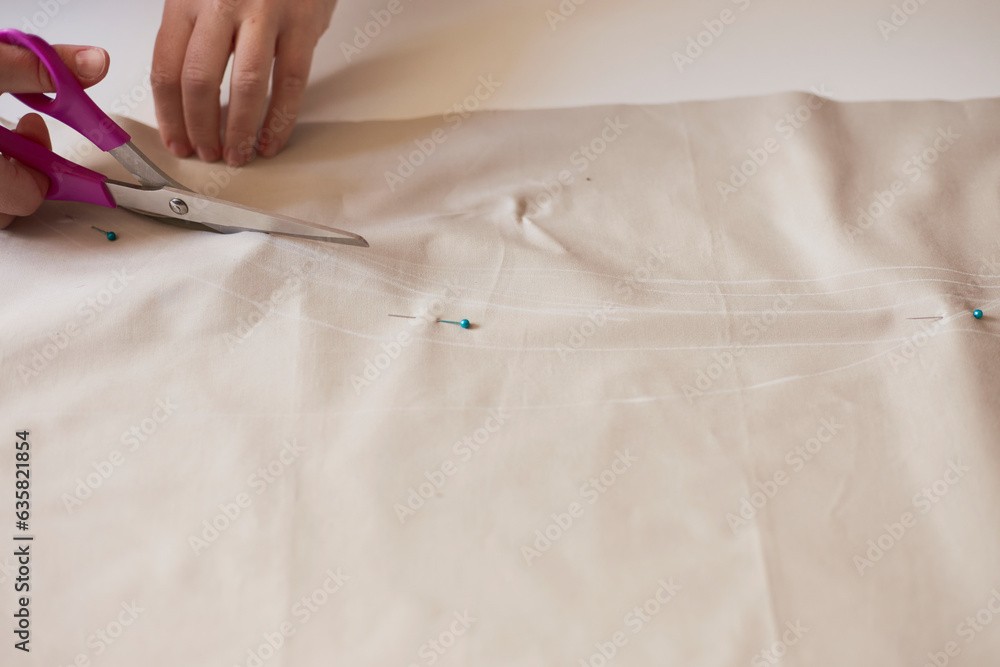 Fototapeta premium Dressmaker cuts dress detail on the sketch lines. Workplace of seamstress.