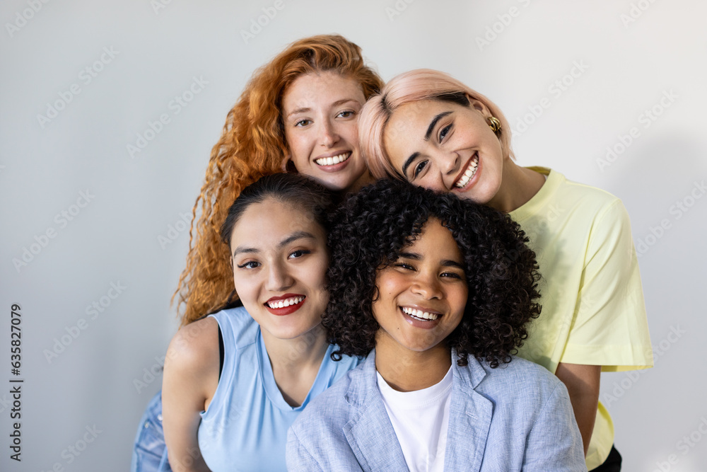 A group of beautiful young women from different races, smiling and looking at the camera against a white wall backdrop. Concept of cross-cultural friendship and diverse beauty. Focus on African girl. A group of beautiful young women from different races, smiling and looking at the camera against a white wall backdrop. Concept of cross-cultural friendship and diverse beauty. Focus on African girl.