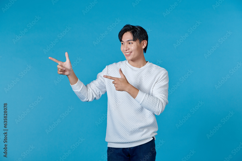 The young man standing on his side pointed his hand to the side with a cheerful expression The young man standing on his side pointed his hand to the side with a cheerful expression
