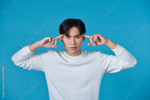 Portrait of smart Asian man at camera and pointing on his head, idea intelligence and imagination concept