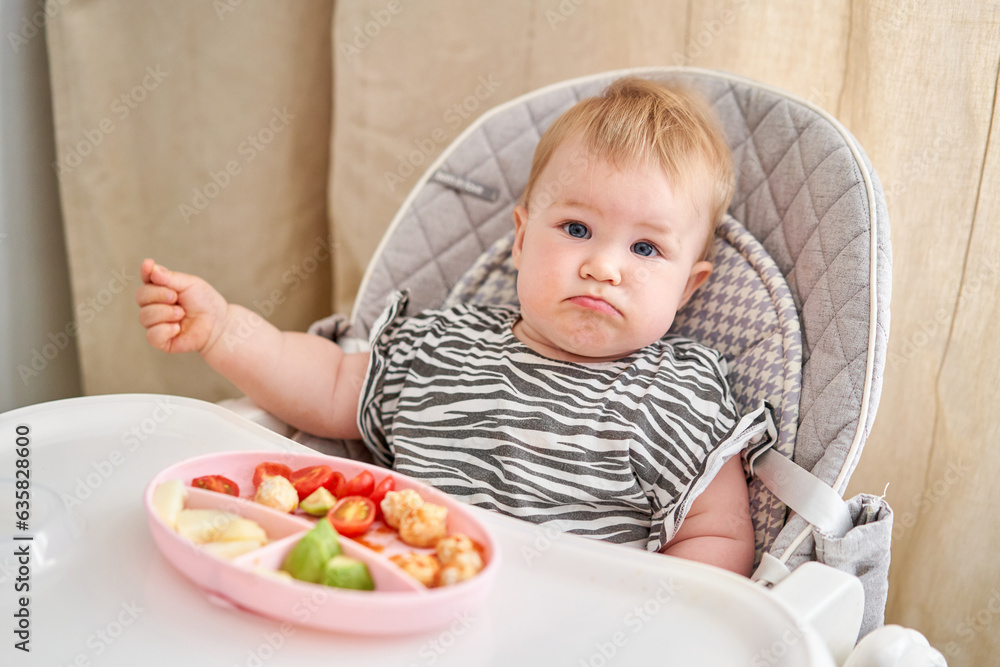 Cute child eats healthy food vegetables and meatballs from dietary meat steamed,. Portraits of a cute 10 months old baby girl. The baby sitting in a special high chair for babies. Cute child eats healthy food vegetables and meatballs from dietary meat steamed,. Portraits of a cute 10 months old baby girl. The baby sitting in a special high chair for babies.