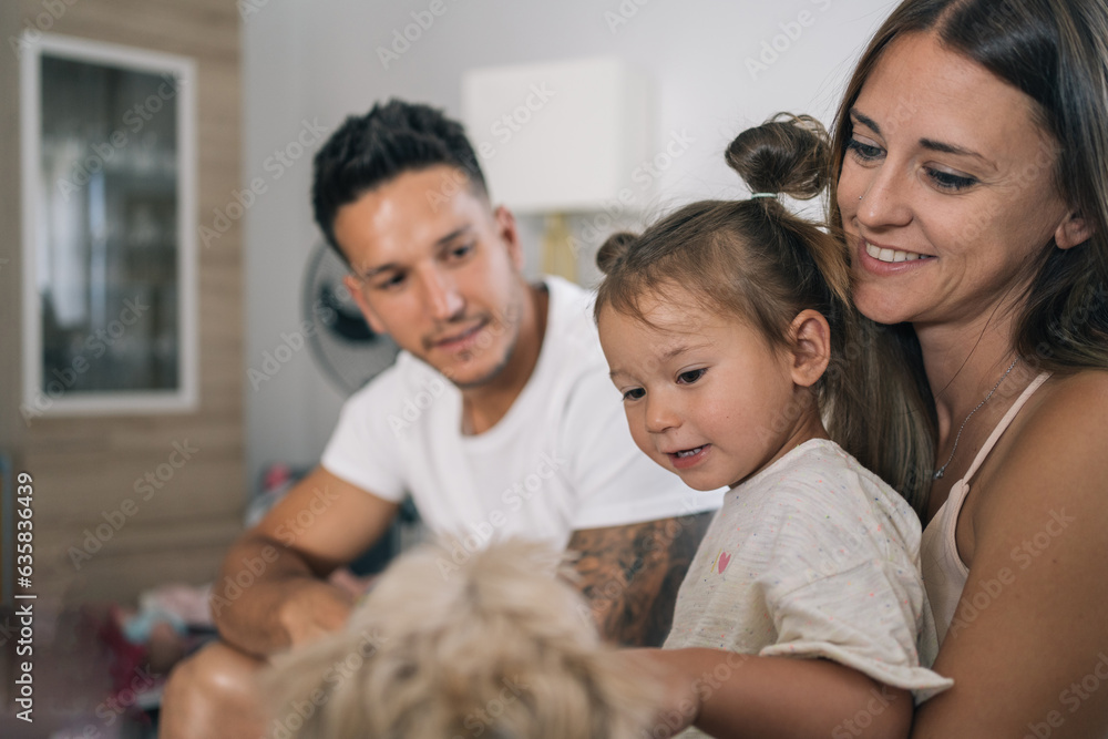 Mother and father sitting on the sofa with their young daughter playing with the dog. Mother and father sitting on the sofa with their young daughter playing with the dog.