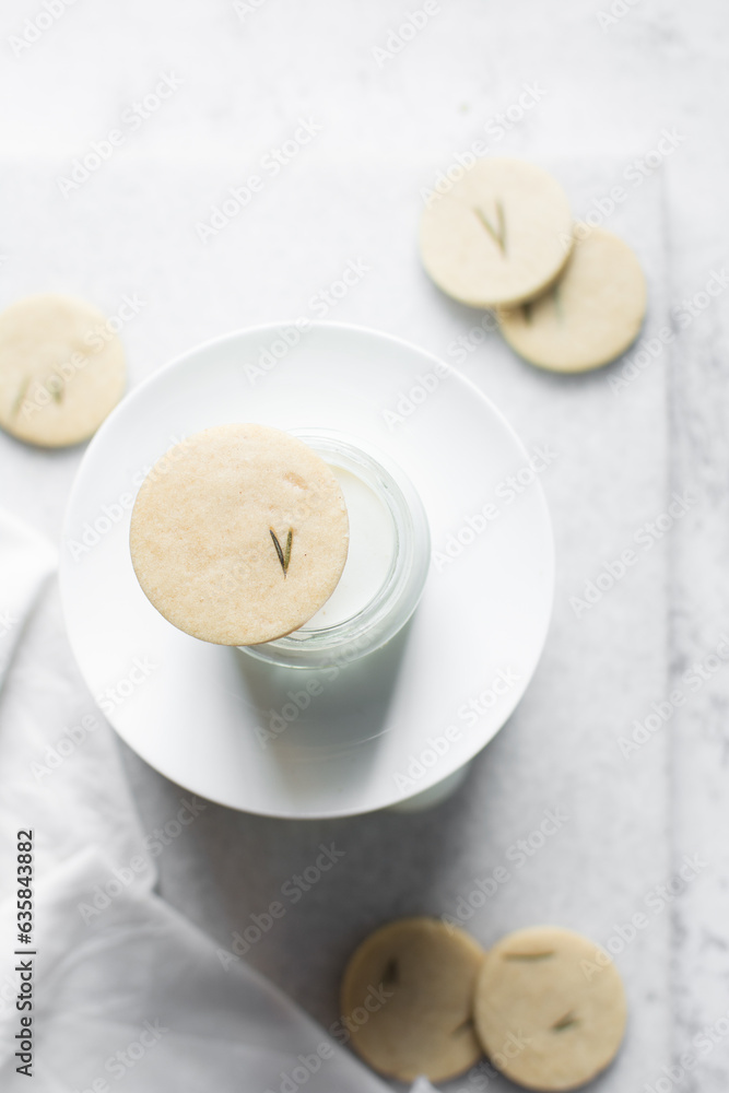 Top view of cut out rosemary sugar cookies on a milk bottle, rosemary cookie on milk on a white background, flatlay of herb sugar cookies Top view of cut out rosemary sugar cookies on a milk bottle, rosemary cookie on milk on a white background, flatlay of herb sugar cookies