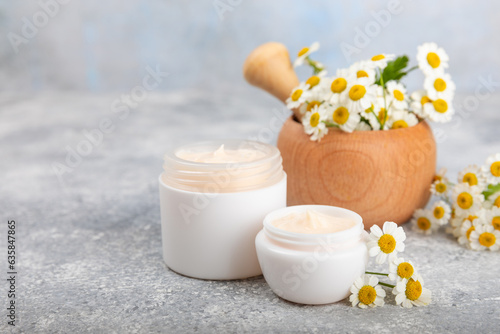 Open jar of cream for face  body and hands with chamomile flower on a blue background. Herbal dermatological cosmetic hygiene cream. Natural cosmetic product. Beauty concept. Cosmetic tube.MOCKUP