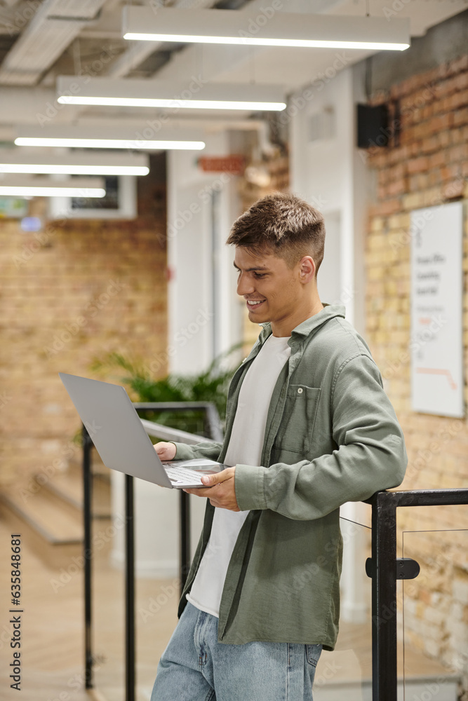 cheerful man using laptop, video call, modern coworking, office environment, generation z, startup