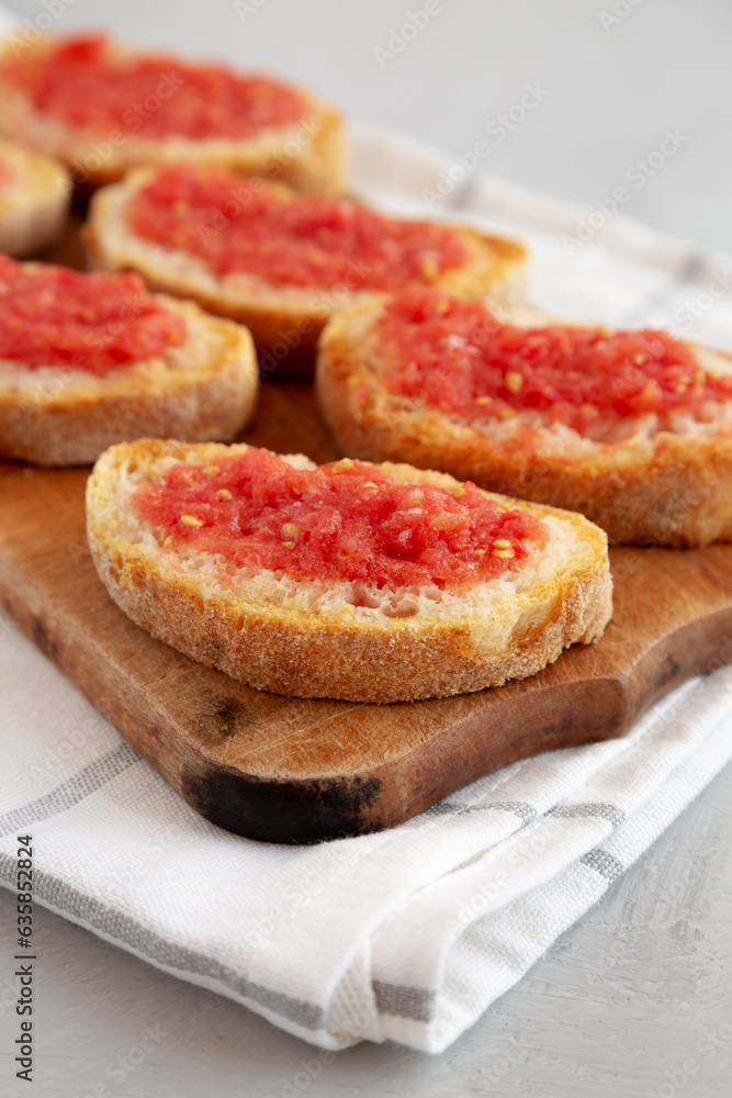 Homemade Pan Con Tomate (Tomato Toast) on a Rustic Wooden Board, side view. Close-up. Homemade Pan Con Tomate (Tomato Toast) on a Rustic Wooden Board, side view. Close-up.