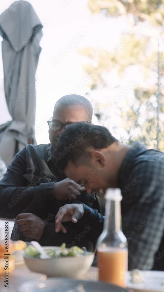 Two Men Laughing at A Cell Phone at an Outdoor lunch Two Men Laughing at A Cell Phone at an Outdoor lunch