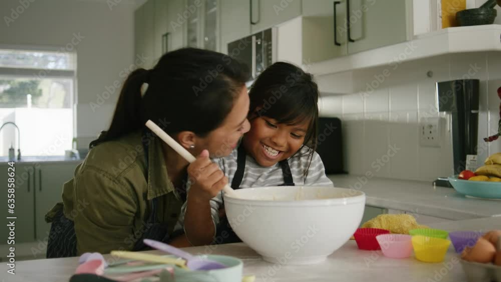 Asian Mother and daughter smiling and looking at the camera laughing in the kitchen Asian Mother and daughter smiling and looking at the camera laughing in the kitchen