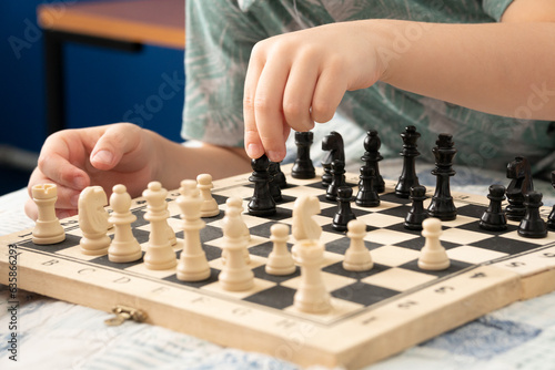 Young boy makes chess move on the board