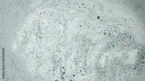 Woman pouring washing powder foam laundry water, top view