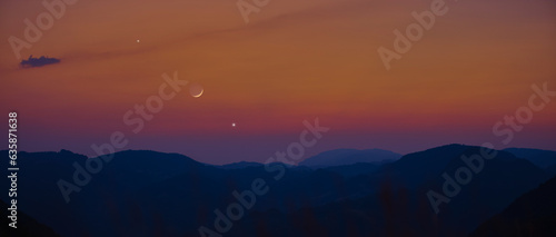 Silhouette of a mountain landscape with Milky Way stars, planets and crescent Moon.