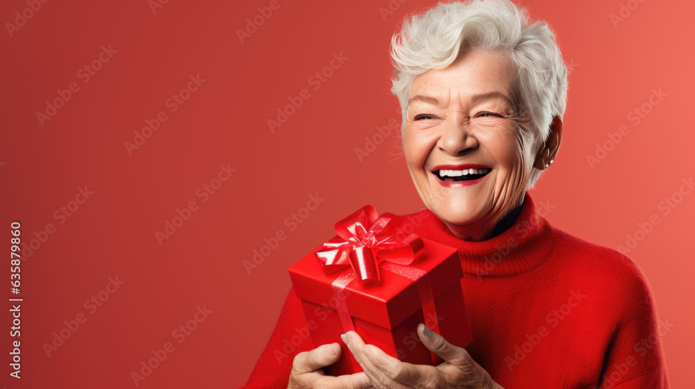 Happy smiling senior woman holding gift box over red background Happy smiling senior woman holding gift box over red background