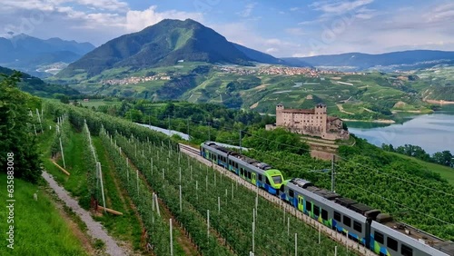 4K Cinematic View of Castel Cles and Santa Giustina Lake — Passenger Train Passing Through Famous Apple Orchards of Val di Non in Trentino Alps Italy