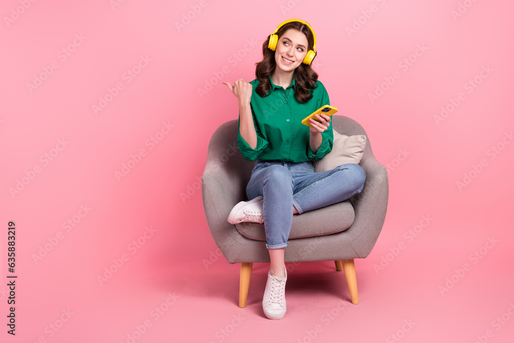 Full length photo of dreamy pretty woman dressed green shirt listening songs thumb empty space isolated pink color background Full length photo of dreamy pretty woman dressed green shirt listening songs thumb empty space isolated pink color background