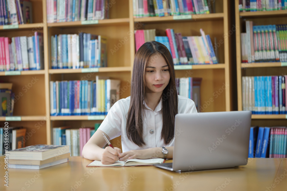 Portrait of an Asian girl college student studying in library doing project assignment and preparing for examination Portrait of an Asian girl college student studying in library doing project assignment and preparing for examination