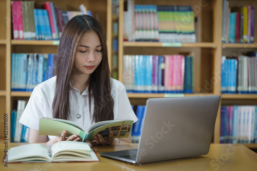 Portrait of an Asian girl college student studying in library doing project assignment and preparing for examination