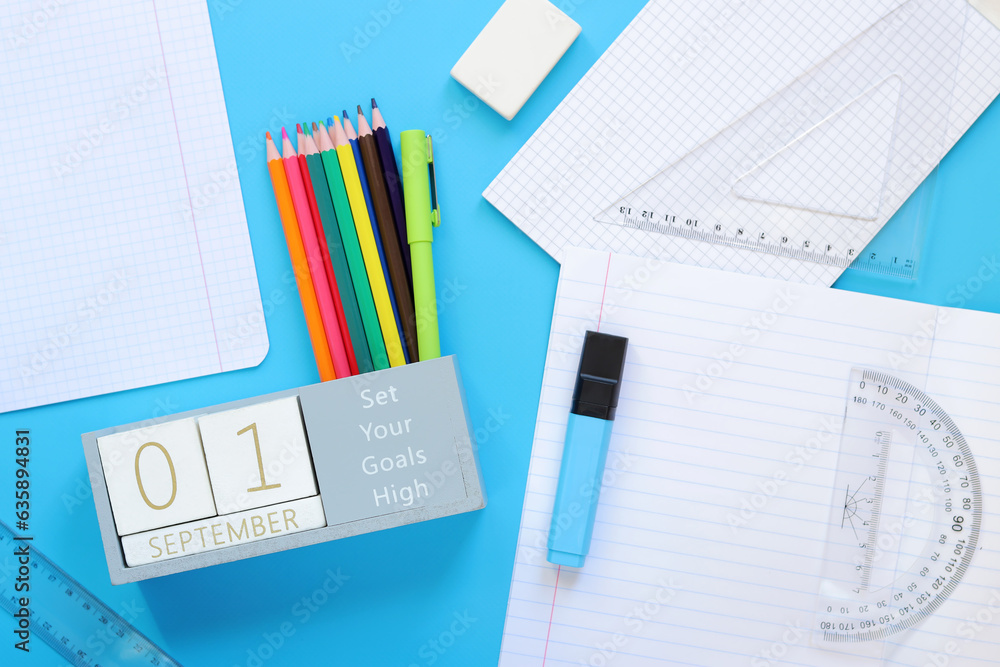 01 September. Image of a wooden calendar for September 1 on a blue table, top view. Back to school. Calendar, pencils and an open notebook. Stationery items. Copy space 01 September. Image of a wooden calendar for September 1 on a blue table, top view. Back to school. Calendar, pencils and an open notebook. Stationery items. Copy space