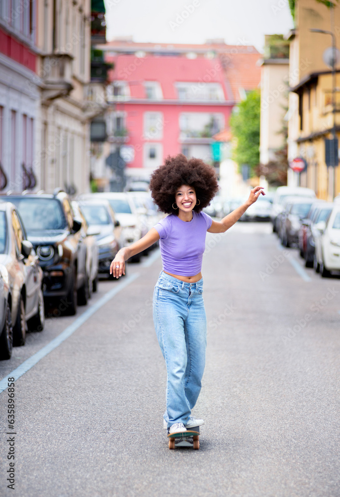 Happy young black woman riding skateboard