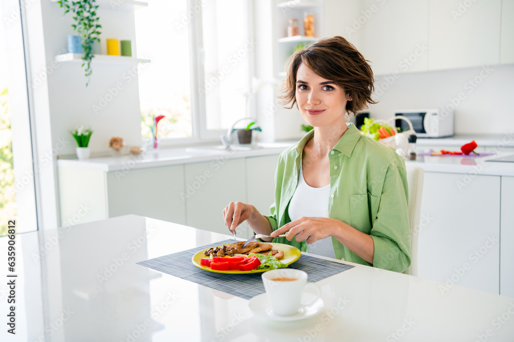 Photo of charming adorable girl wear green shirt enjoying tasty dinner coffee indoors kitchen room Photo of charming adorable girl wear green shirt enjoying tasty dinner coffee indoors kitchen room