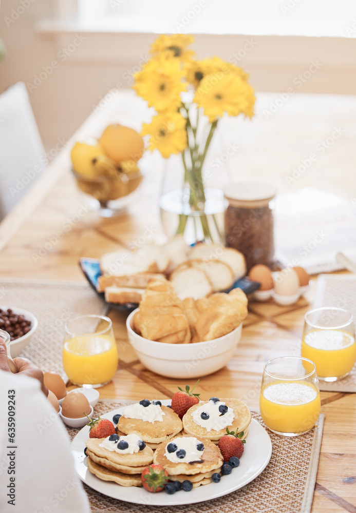 Pancakes, breakfast and orange juice on table in home in the morning. Bread waffle, hands and fruits for eating, healthy diet and strawberry cream in wellness nutrition, blueberry food and egg meal.