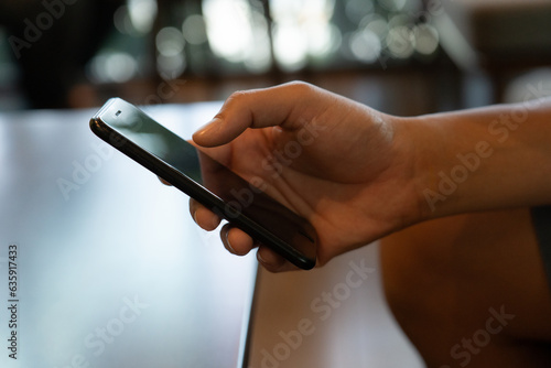 The firm grip of a male hand on a sleek mobile phone reveals a modern shopping experience. With deft fingers  he navigates through a virtual marketplace  exploring a diverse array of products.close up