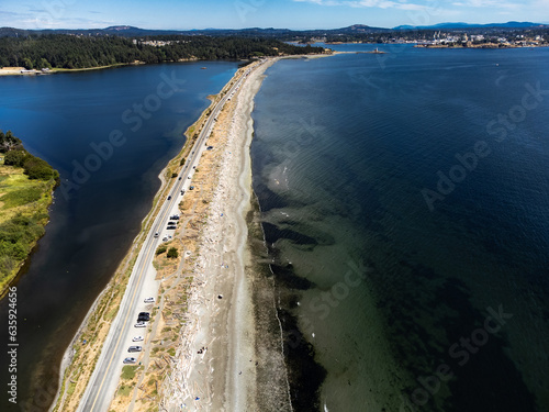 Aerial sand spit with a long straight road with people on vacation and cars parked in Victoria British Columbia Canada.. © Ramon Cliff