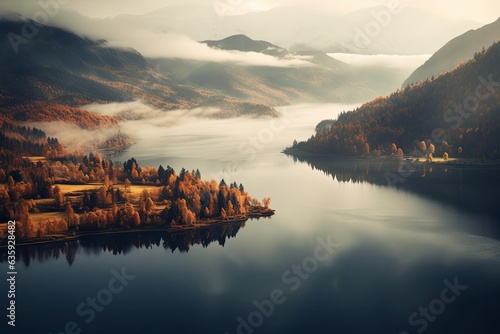 a lovely lake surrounded by hills, photographed from above in fall with a hazy sky